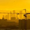Инвестиции в новостройки: башенный кран на фоне жилых кварталов Москвы
