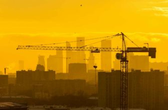 Инвестиции в новостройки: башенный кран на фоне жилых кварталов Москвы