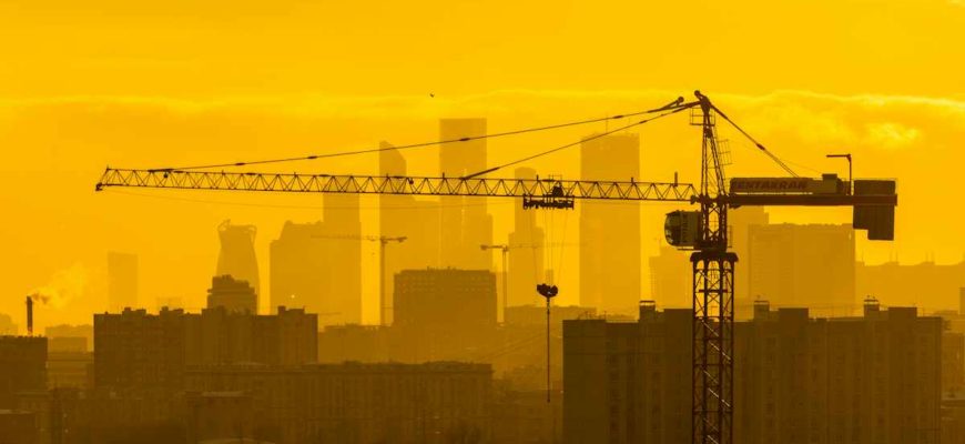 Инвестиции в новостройки: башенный кран на фоне жилых кварталов Москвы